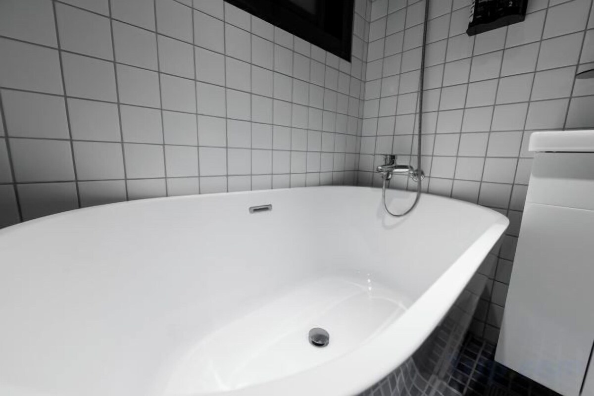 A white bathtub in a bathroom with tiled walls and a white sink.