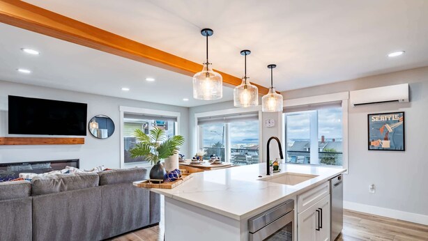Una cocina moderna con una isla grande, electrodomésticos de acero inoxidable e iluminación colgante.