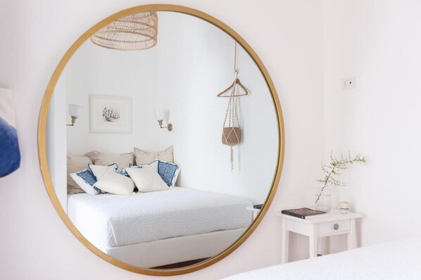 A bedroom with a round mirror, bed, bedside table, and wall-mounted decor. - Villa Mina By Napoliapartments (Vietri sul Mare)