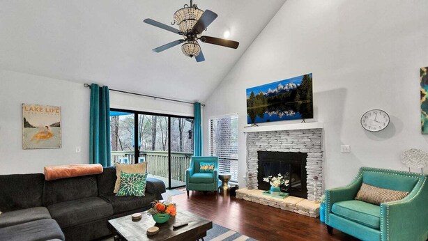 A living room with a sofa, armchairs, a coffee table, a fireplace, and a large window.