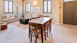 A spacious living area with a wooden dining table, beige sofas, and a large window. - Retrocantina (Montefalco)