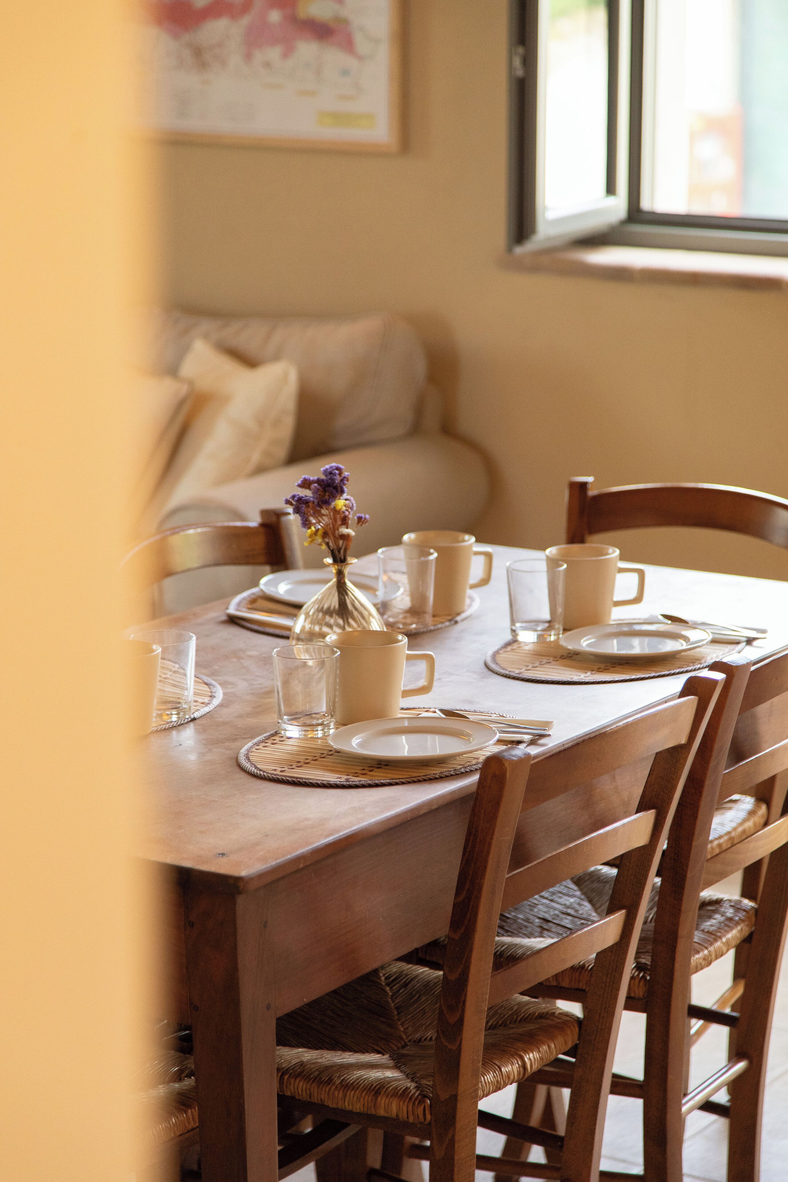A dining table set with plates, cups, and a vase of flowers.
