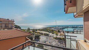 Un balcon avec vue sur un port de plaisance et la mer.