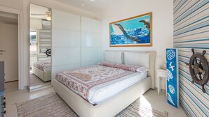 Une chambre à coucher avec un lit, un tableau, un gouvernail de bateau et un mur à rayures.