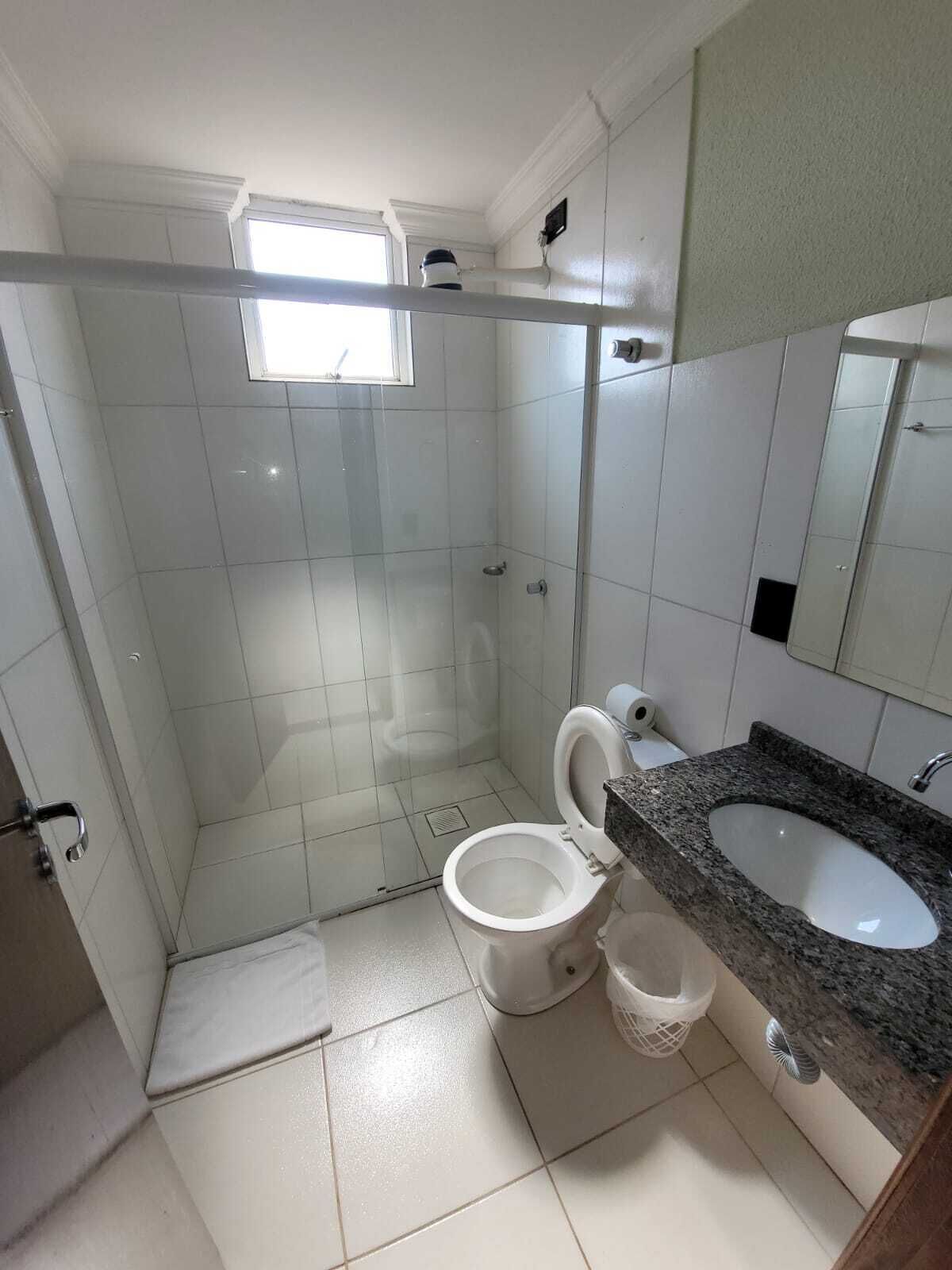 A bathroom with a glass-enclosed shower, a toilet, and a sink with a granite countertop.