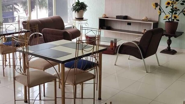 Una sala de estar moderna con comedor, un televisor de pantalla plana montado en una pared de madera y un gran ventanal con vistas a zonas verdes.