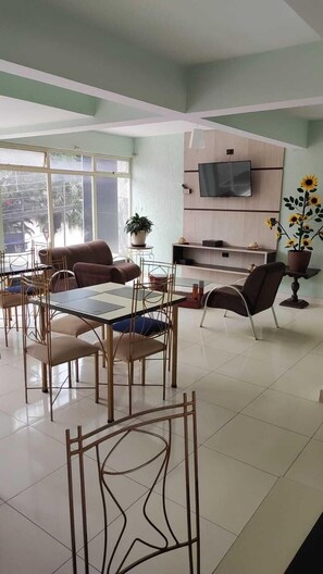Una sala de estar moderna con comedor, un televisor de pantalla plana montado en una pared de madera y un gran ventanal con vistas a zonas verdes.