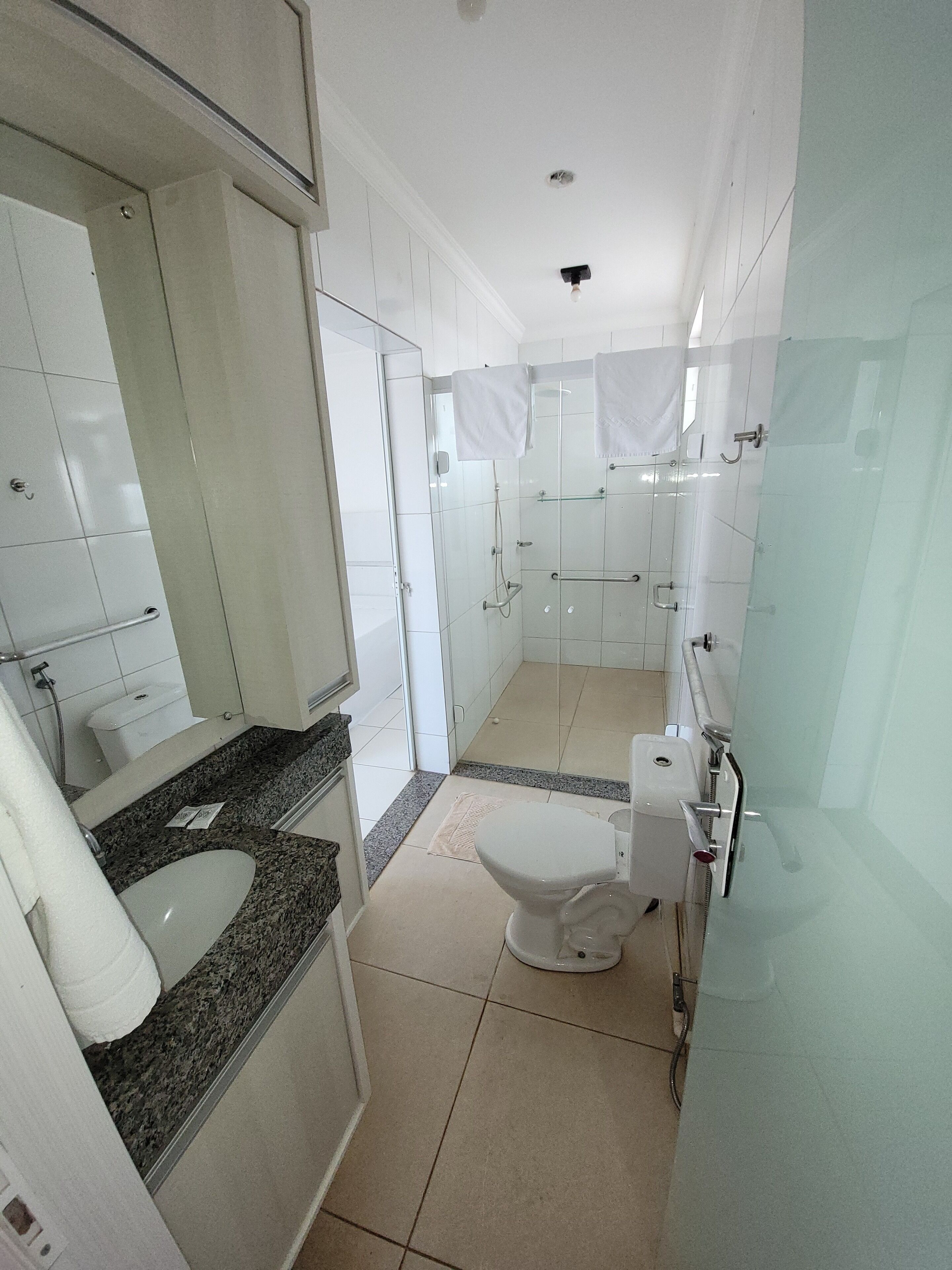 A modern bathroom with a white sink, toilet, and shower area.