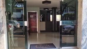 Entrada de hotel con puerta de cristal, mostrador de recepción y señal que indica un espacio para uso de negocios y personal.