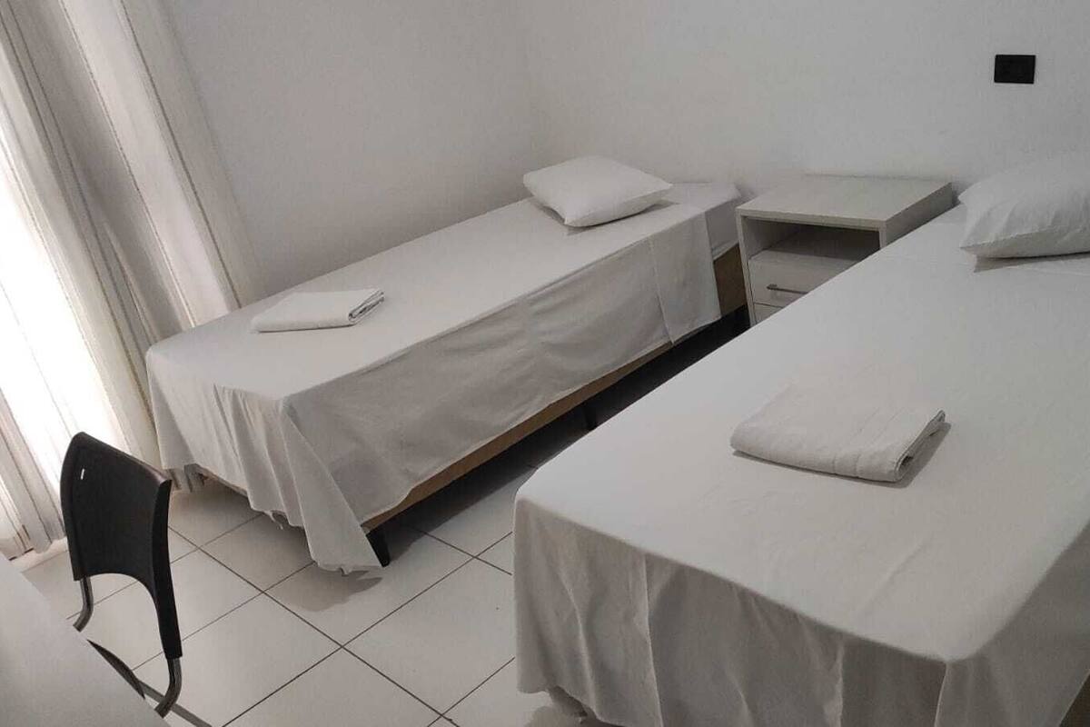 Una habitación con dos camas individuales, una mesita y una silla.