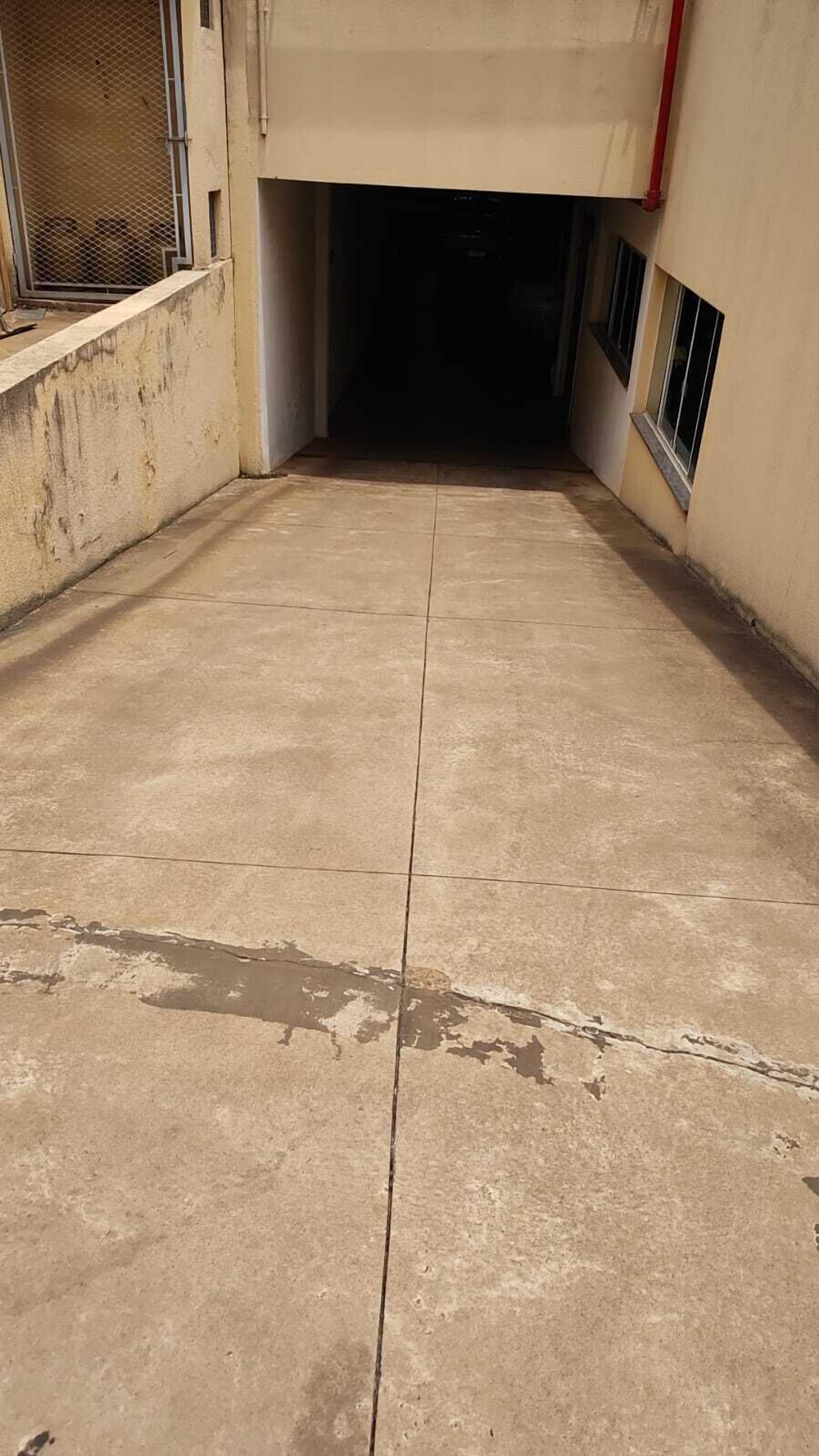 A concrete floor with visible cracks and a metal fence on the left.
