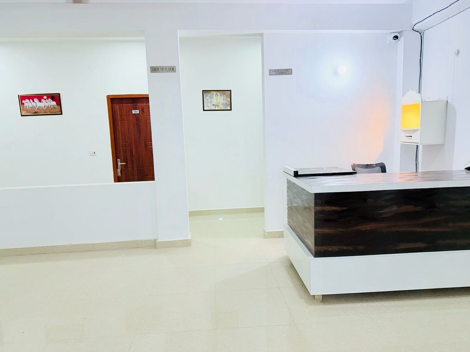 A reception area with a modern desk, a wooden door, and a wall-mounted sign indicating the ground floor.