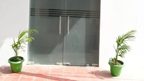 Ein Hotel Eingang mit einem Schild, auf dem 'HOTEL RITURAJ' steht, und einer großen Glasdoor. An beiden Seiten der Tür befinden sich je ein Blumentopf.