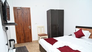 Ein Schlafzimmer mit einem Bett, einem Kleiderschrank, einem Sessel und einem Fernseher.