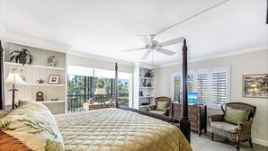 A spacious bedroom with a large bed, a ceiling fan, and a view of palm trees through the windows. - Indies West at The Moorings (Naples)