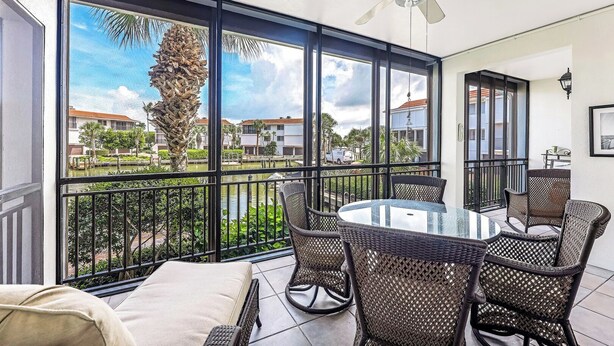 A balcony with a glass door, wicker furniture, and a ceiling fan. - Indies West at The Moorings (Naples)