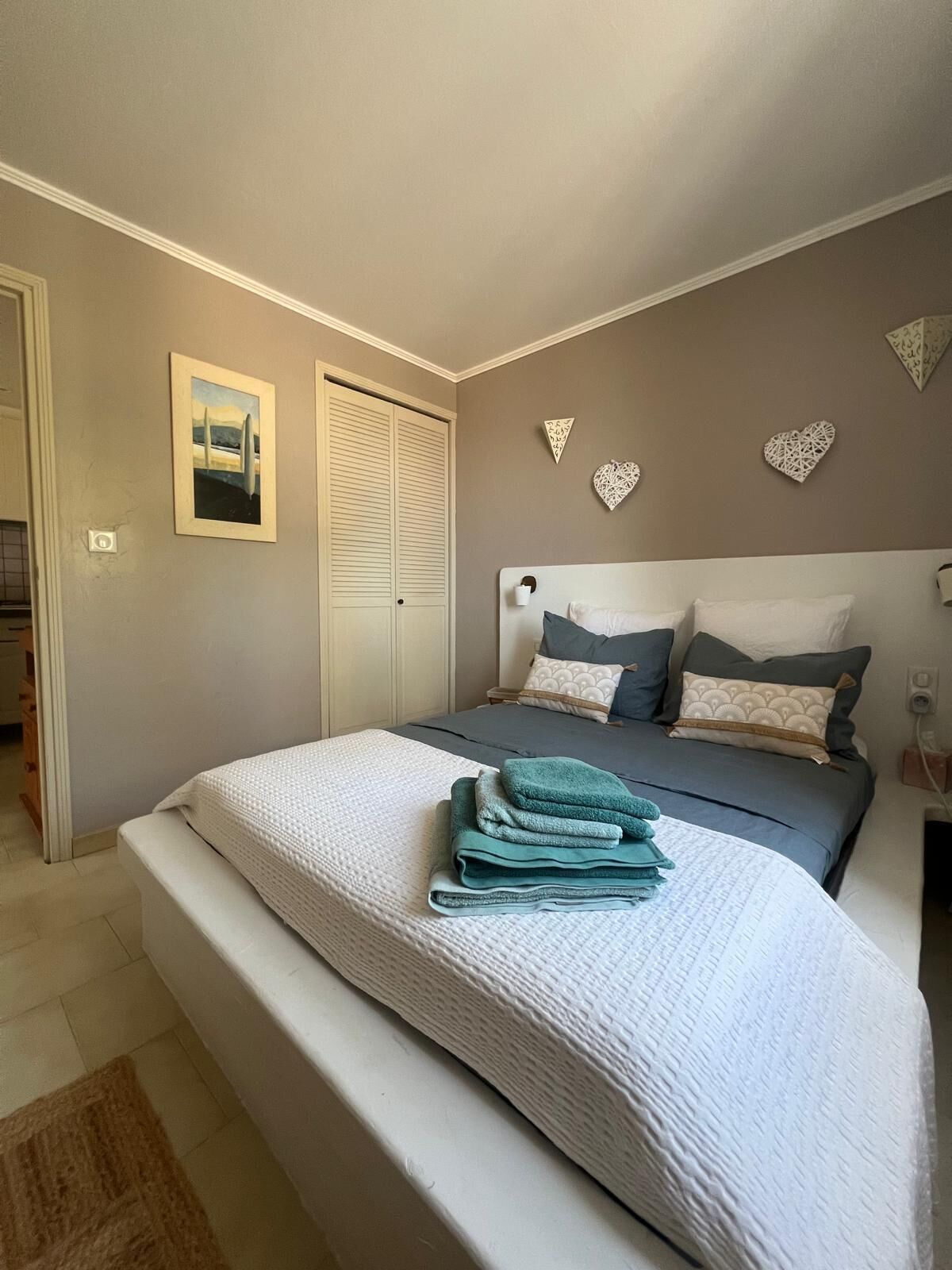 Une chambre à coucher avec un lit, une table de chevet, une commode et une porte.