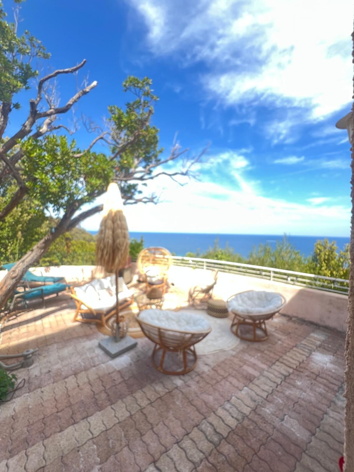 Une terrasse avec des meubles d’extérieur, une vue sur l’océan et des arbres.