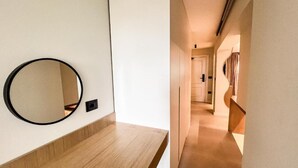 Un couloir d’hôtel moderne avec un comptoir en bois et un grand miroir rond accroché au mur.