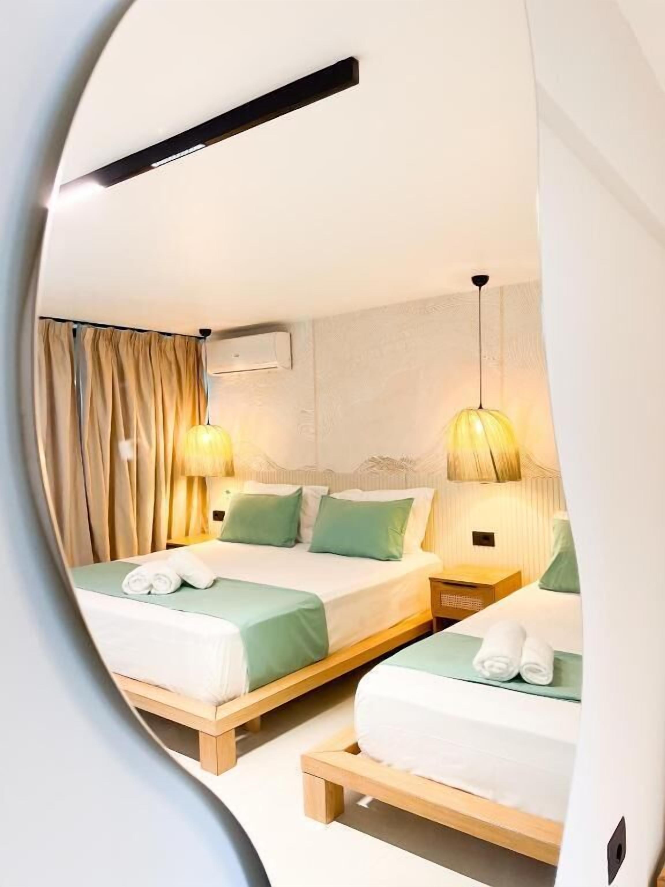 Una camera d'albergo con due letti, una ventola a soffitto e un condizionatore d'aria a parete.