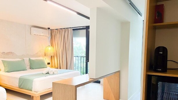 Une chambre d’hôtel moderne, équipée d’un lit, d’une table de chevet et offrant une vue sur l’extérieur.