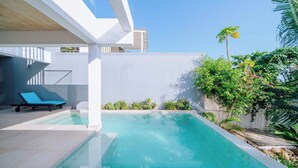 A modern outdoor pool area with a clear blue pool, a lounge chair, and lush greenery. - Fumba Town Private Residences (Kombeni)