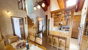 A spacious kitchen with wooden cabinets, a central island with stools, and a staircase leading to another level. - Apartman Talia 1 (Dramalj)