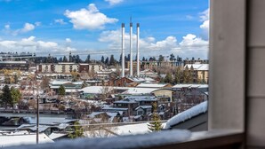 A snowy urban landscape with industrial buildings, including tall chimneys, and residential areas. - New! Old Mill Lookout–Mountain Views, Fireplace, Dog Friendly (Bend)