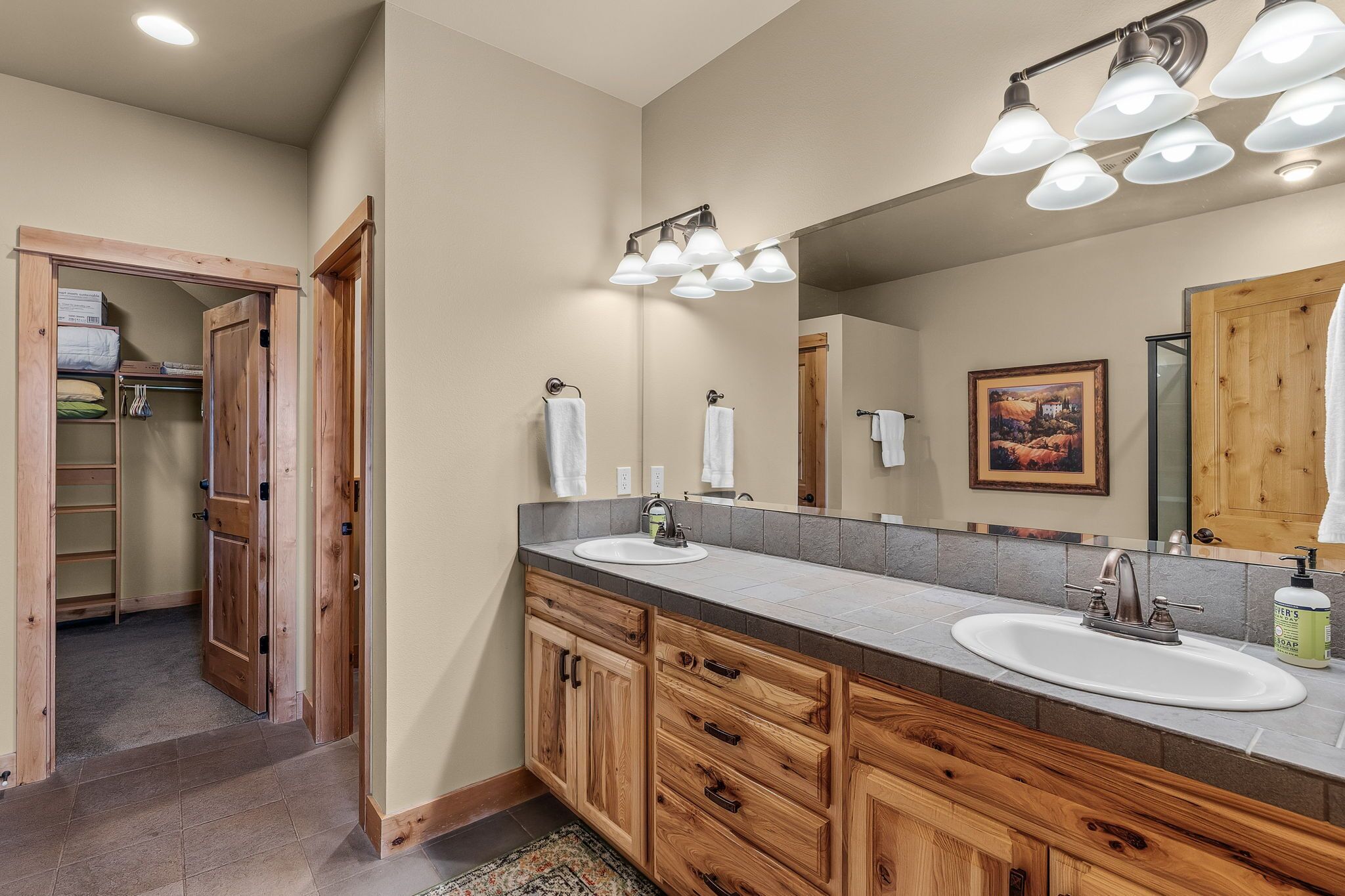 A bathroom with wooden cabinets, a large mirror, and a sink.