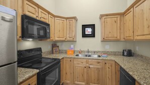 Une cuisine avec des meubles en bois, un réfrigérateur en acier inoxydable, un four à micro-ondes, une cuisinière, un évier et un grille-pain.