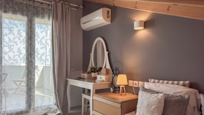 A bedroom with a bed, bedside table, lamp, and a dresser. There is a window with curtains, an air conditioning unit, and a wall-mounted light. - Alisahni Villa (Daratsos)