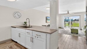 Una cocina con un lavabo, armarios y un reloj en la pared.