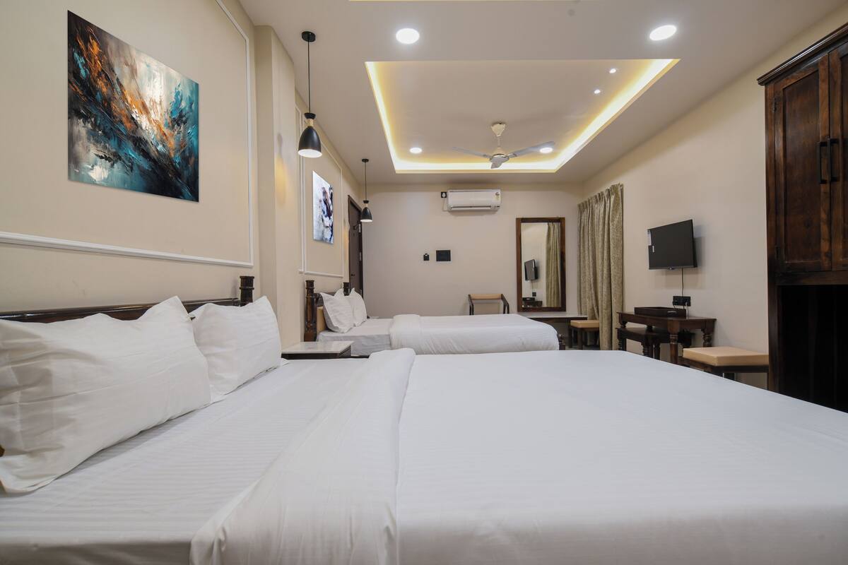Une chambre d’hôtel avec deux lits, un ventilateur de plafond, des spots encastrés, un téléviseur à écran plat et un tableau au mur.