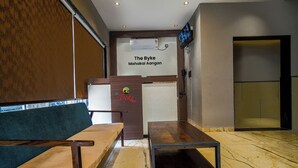 Ein Empfangsbereich mit einer Holzbänkl, einem kleinen Tisch und einem an der Wand befestigten Fernseher.