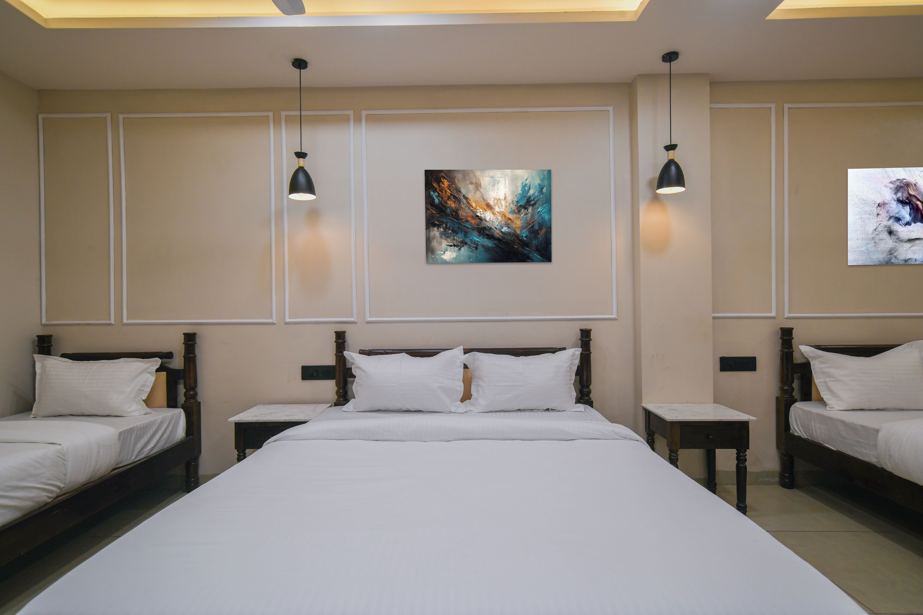 Habitación de hotel con dos camas individuales, una cama grande y una lámpara de techo.