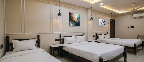 A hotel room with three single beds, a ceiling fan, recessed lighting, and artwork on the walls.