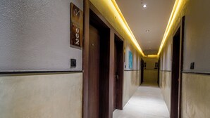 Ein Hotelgang mit Holztüren, einer Uhr und einem Schild, das die Zimmernummer 002 anzeigt.