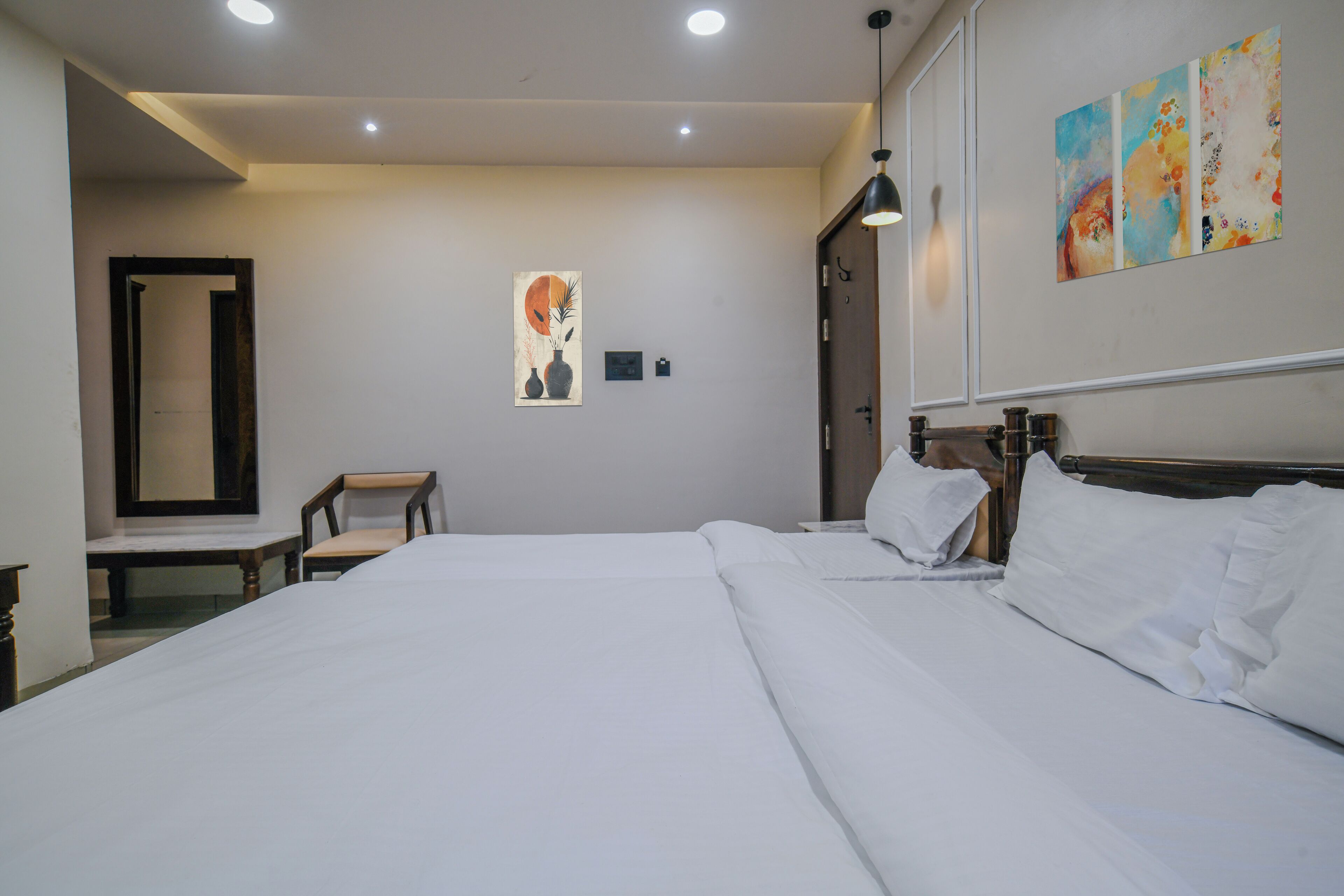 Habitación de hotel con una cama grande, una silla, un escritorio y un cuadro en la pared.