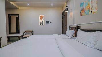 Habitación de hotel con una cama grande, una silla, un escritorio y un cuadro en la pared.