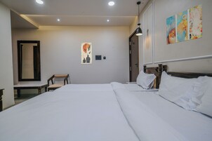 Habitación de hotel con una cama grande, una silla, un escritorio y un cuadro en la pared.