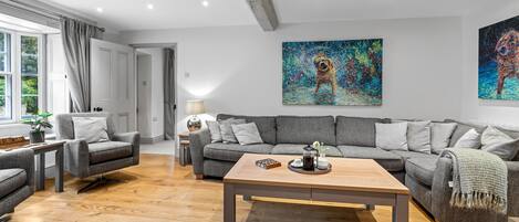 A modern living room with a grey sofa, a wooden coffee table, and a painting on the wall.