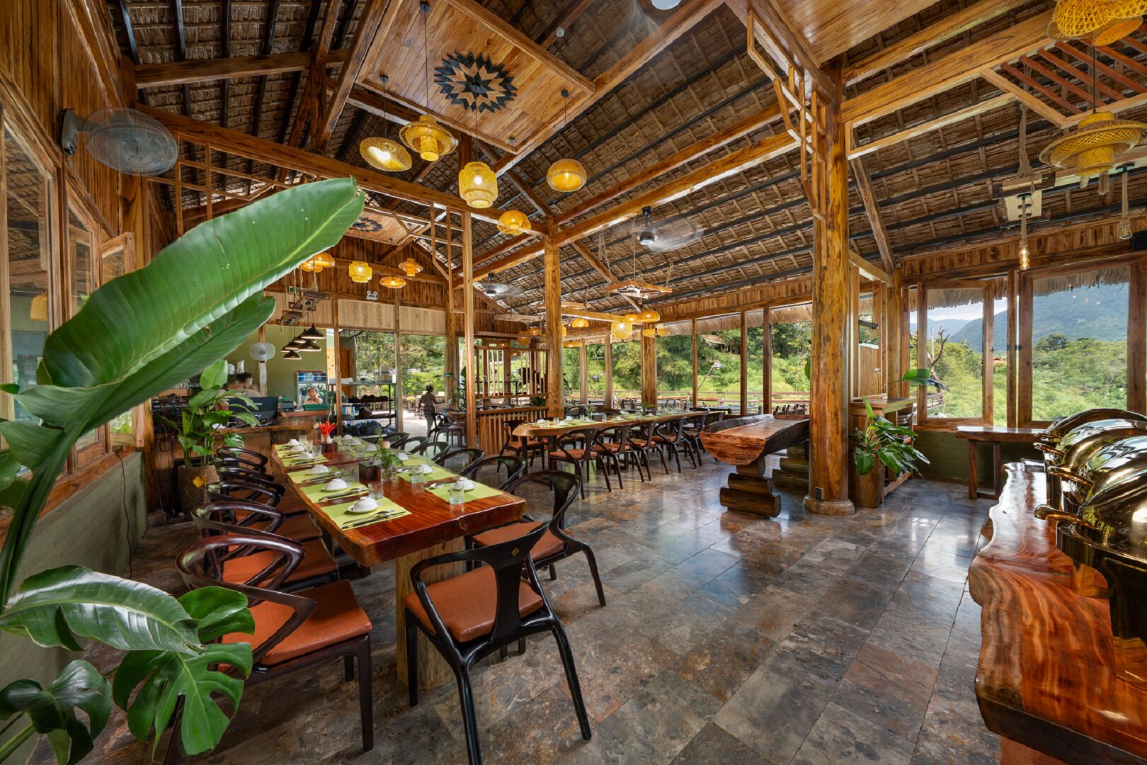 Un restaurante espacioso con techos altos, vigas de madera y grandes ventanales que ofrecen vistas al exterior.