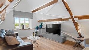 Une chambre de style loft moderne, dotée d’une grande fenêtre, d’un téléviseur à écran plat, d’un canapé et d’une table à manger.