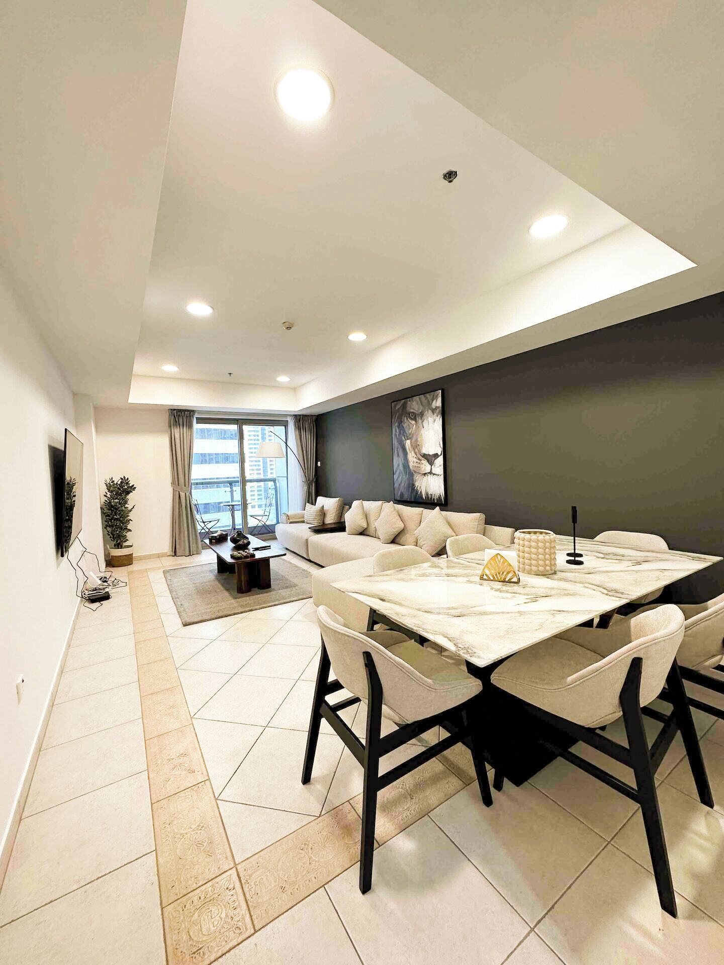 A modern living room with a large sofa, a dining table, and a large window.
