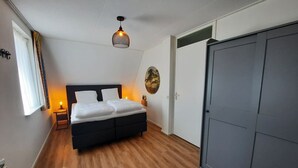 A bedroom with a bed, bedside table, lamp, and wardrobe.