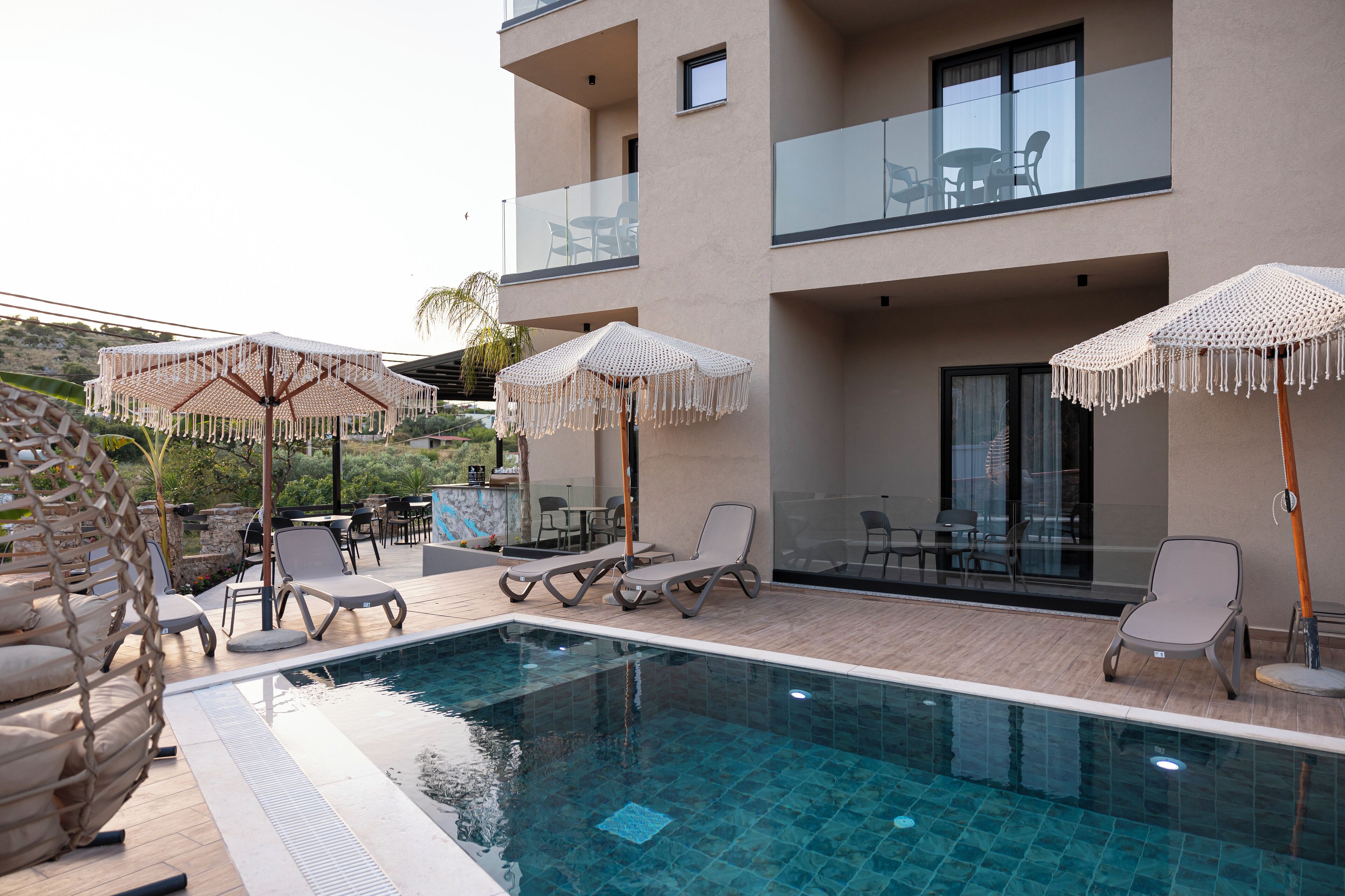 An outdoor swimming pool with lounge chairs and umbrellas, a bar, and a dining area with tables and chairs.
