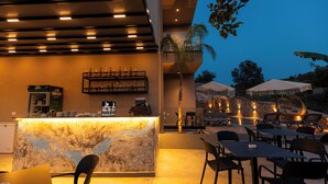 Un espace bar extérieur doté d’un comptoir en marbre, de sièges et de parasols.