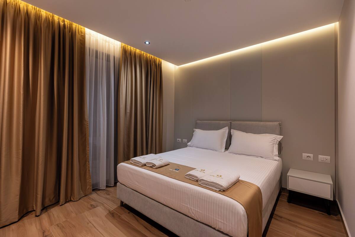 Moderni hotellihuone, jossa on suuri sänky, yöpöytä ja verhot.