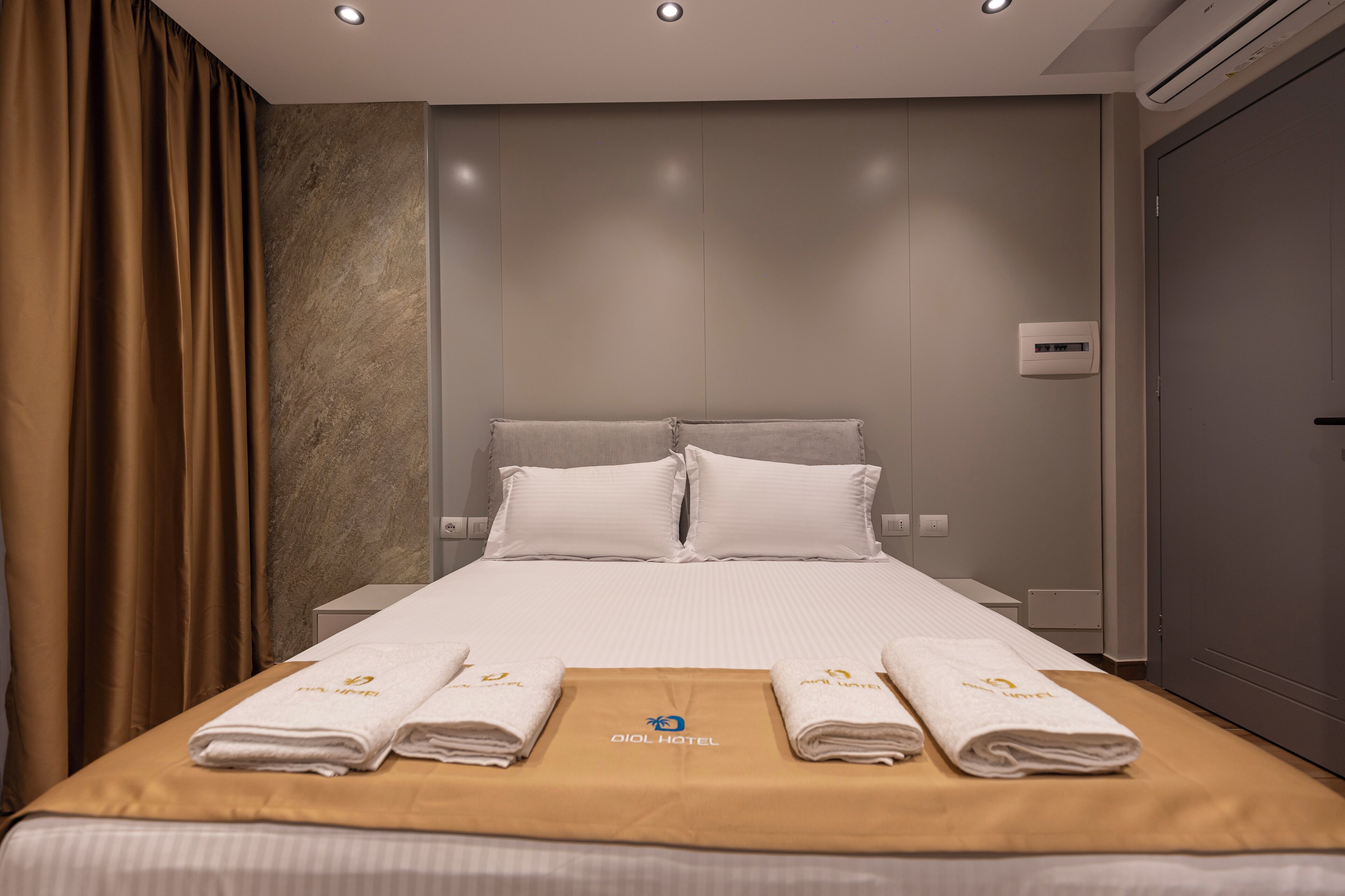 Una habitación de hotel con una cama bien hecha, un minibar y un equipo de aire acondicionado instalado en la pared.