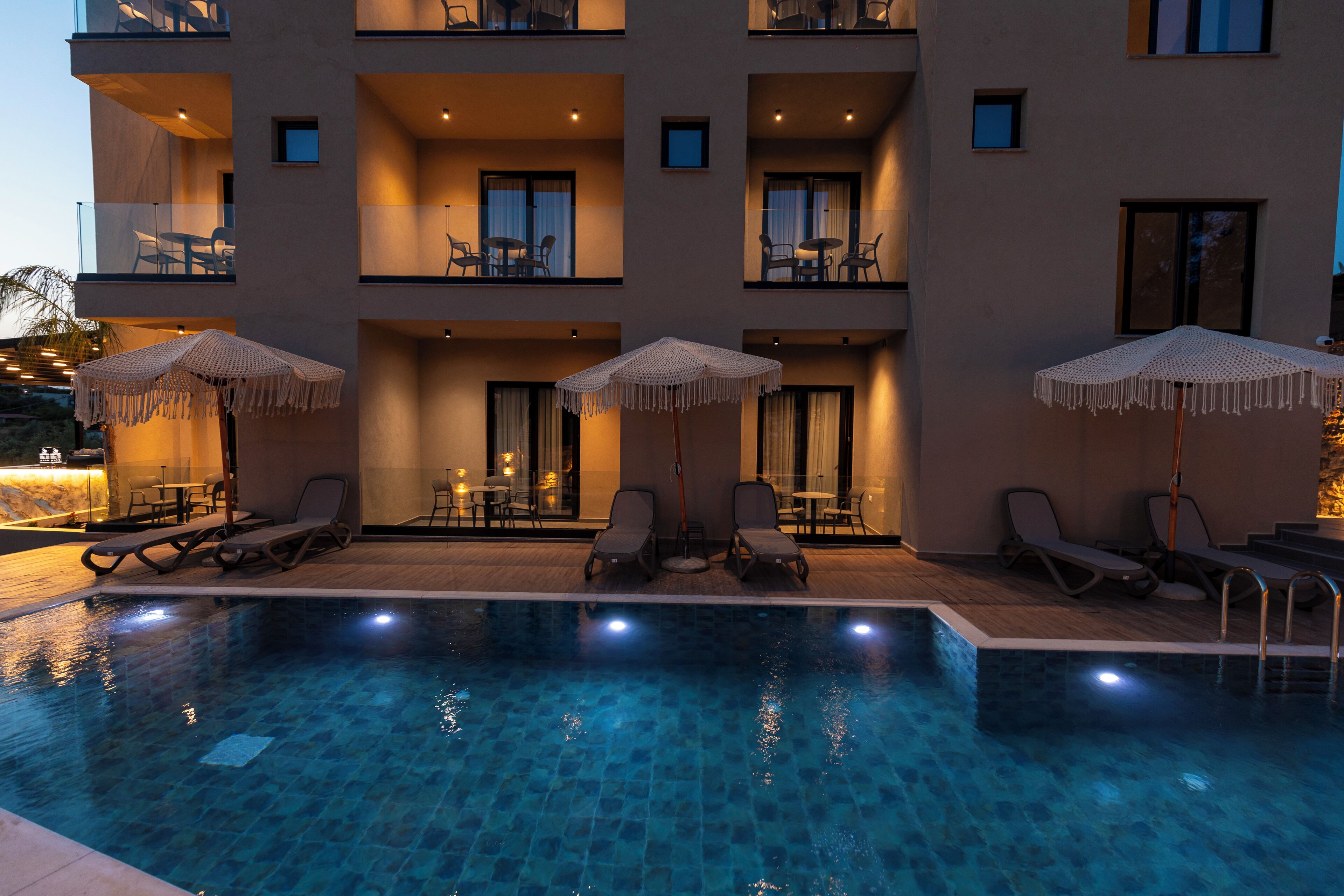 A hotel with a swimming pool, outdoor seating, and balconies.